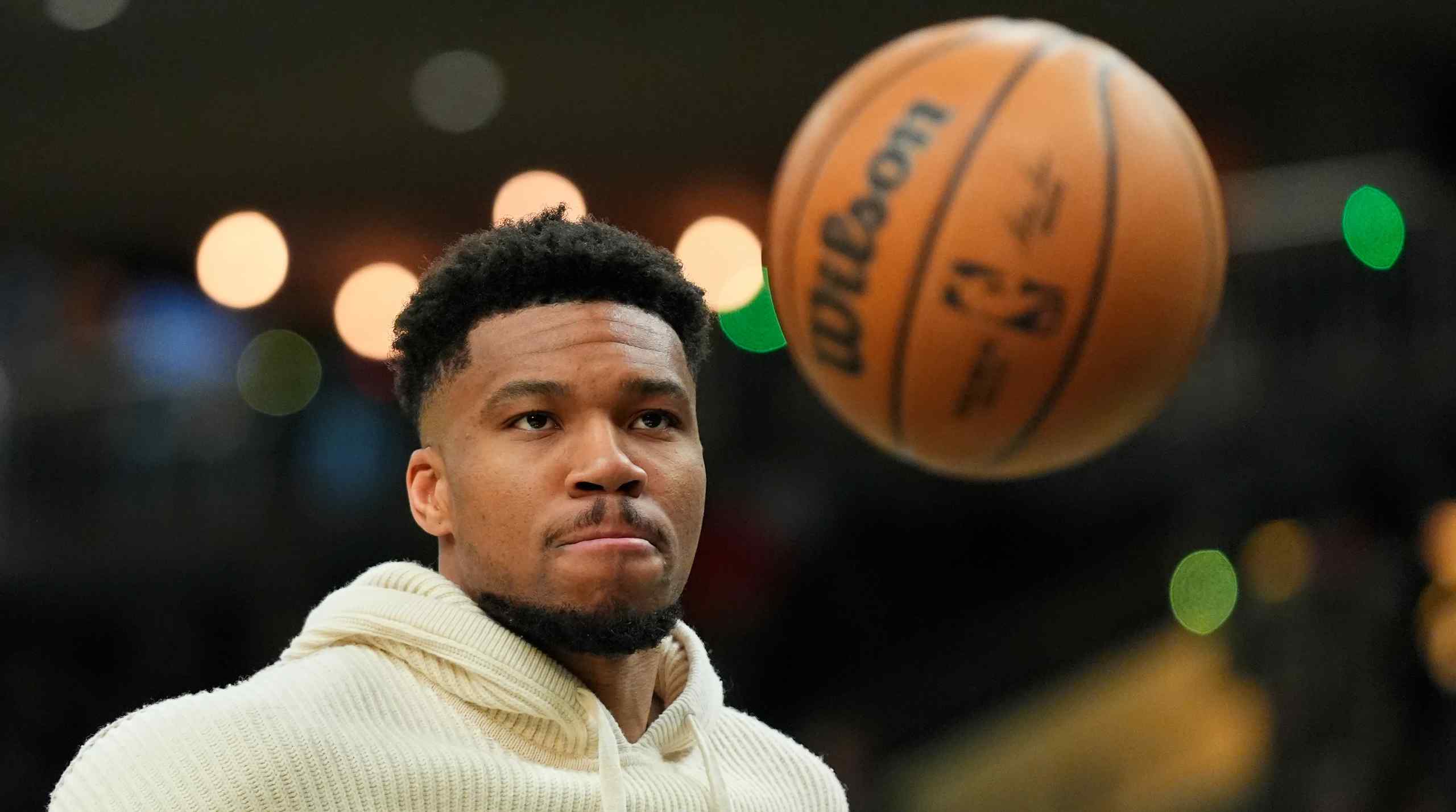 Giannis Antetokounmpo staring at a basketball in the air.